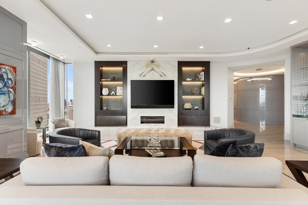 Welcome to this extraordinary 38th-floor residence at the exclusive Four Seasons Private Residences at One Dalton, where exceptional service, sophisticated design, and sweeping Charles River views come together at one of Boston’s most prestigious addresses. This exceptional 3-bedroom, 3.5-bath home spans more than 3,200 square feet and features panoramic views of Back Bay, Cambridge, the Charles River, and spectacular sunsets, beautifully framed by floor-to-ceiling windows in every room. Meticulously customized by Sanborn Custom Builders, the residence showcases refined interiors with a striking custom fireplace and marble-clad feature wall, designer lighting, and elegant porcelain flooring throughout. Private elevator access opens directly into your own private foyer, creating an exceptional sense of privacy and exclusivity. The expansive living and entertaining spaces flow seamlessly into a bespoke gourmet kitchen, complemented by a rarely available additional family room, ideal for relaxed everyday living or lavish entertaining. Residents enjoy the legendary Four Seasons standard of white-glove service and exclusive access to the 50/50 Club, along with an exceptional collection of amenities including a 65-foot heated lap pool, spa, state-of-the-art fitness center, golf simulator, private theater, and dining at the renowned Zuma restaurant. Two valet parking spaces complete this exceptional offering. A truly remarkable home offering extraordinary views, exceptional privacy, and a spectacular front-row seat to all that Boston has to offer.