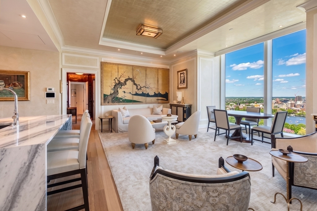 An exquisite blend of comfort, style, and unmatched craftsmanship in the prestigious One Dalton. Boasting breathtaking 180 degree views from the Charles River and  Cambridge to Logan Airport and Boston Harbor, this residence has top-tier finishes throughout, including Cerused oak flooring, high ceilings with moldings, low voltage recessed lighting, extensive audio visual, limestone gas fireplace anchoring the living space and all push-button controlled window treatments.  A chef’s dream, the custom-designed kitchen sets the stage for a home defined by luxury with its marble waterfall island, Wolf appliances and direct, dramatic Boston views. The primary suite serves as a serene retreat, featuring a dressing room, a spa-like bath with radiant heated, sunburst designed marble floors, a soaking tub, and Waterworks fixtures. A second bedroom offers its own en-suite marble bath, while the sophisticated den, complete with custom built-ins and library lighting sits adjacent to a third full bathroom. Every inch of this home exudes thoughtful design, crafted by an acclaimed Boston team. Located in the highly sought after main spine of the building, only 2 other units are located on this floor and access to the 50/50 Club is just a quick ride down on the same elevator. This is truly one of the most bespoke properties in Boston.