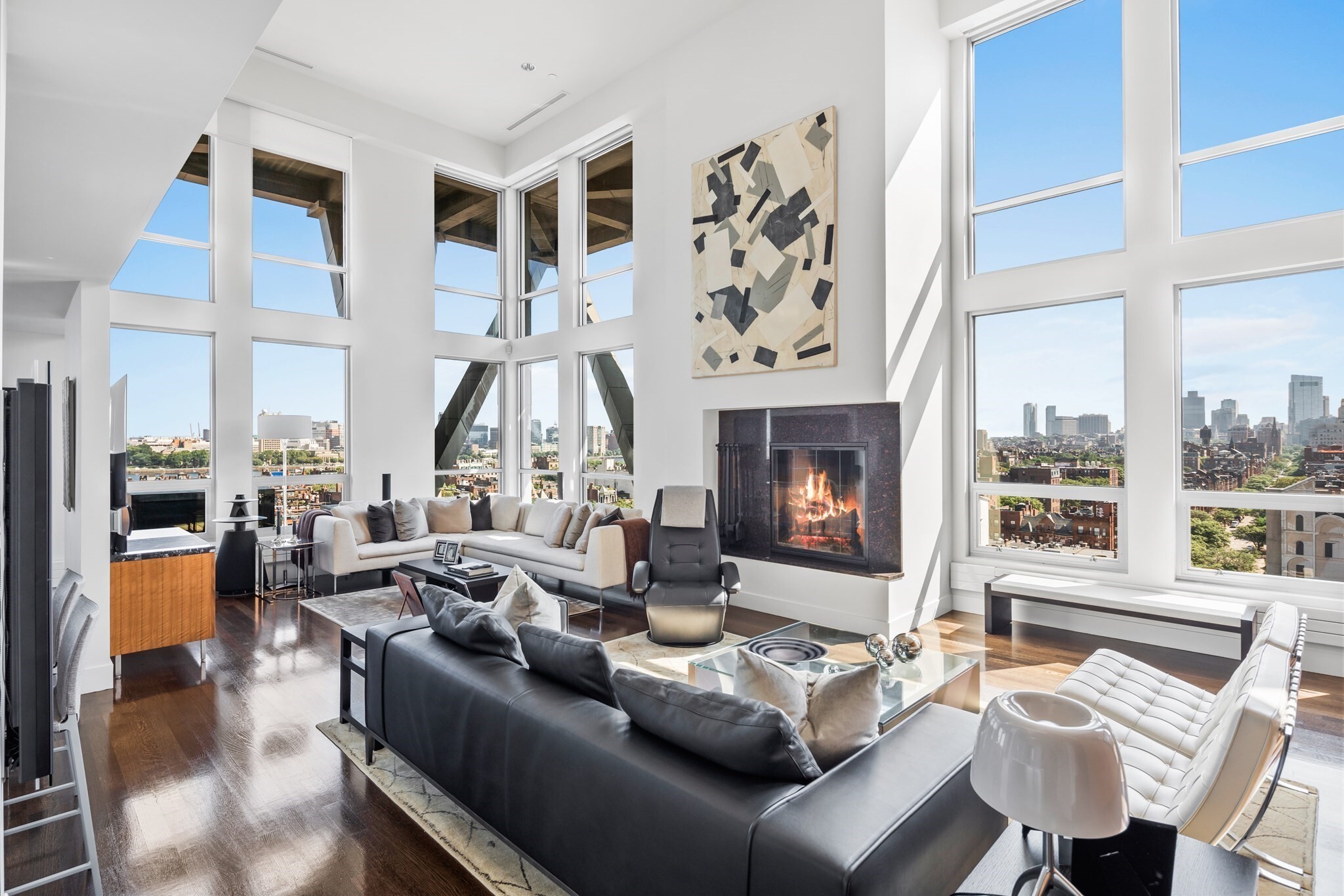 Introducing Penthouse 810 at 360 Newbury, a rare opportunity to own one of the building's most exceptional residences. Defined by soaring 20-foot ceilings, dramatic walls of glass, and breathtaking city views, this architecturally significant home offers an extraordinary sense of scale and light. The spectacular double-height living room is anchored by a striking fireplace and framed by floor-to-ceiling windows overlooking Back Bay, the Charles River, and Boston's skyline beyond. An open-concept layout seamlessly connects the living, dining, and kitchen spaces, creating an ideal setting for both everyday living and sophisticated entertaining. Rich hardwood floors, custom finishes, and a sculptural staircase enhance the residence's contemporary design. Located within Frank Gehry's iconic 360 Newbury, residents enjoy concierge services and an unparalleled location at the crossroads of Back Bay and Newbury Street, moments from the city's finest shopping, dining, and cultural attractions.