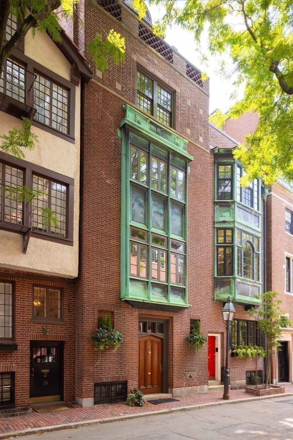 Located on a picturesque tree-lined street on the Flat of the Hill, this 1914 townhouse spans 5,194 square feet, offering four bedrooms, five and a half bathrooms and two private outdoor spaces. The main floor opens with a gracious foyer leading to an elegant dining room. One level below, the garden floor unfolds around a generous kitchen, dining area, and family room, all opening directly to a private brick patio—a rare, quiet outdoor retreat in the heart of the city. Above the main floor, the house reveals one of its most remarkable spaces: a double-height great room (living room/library), with an open balcony on the level above overlooking the room. The scale is extraordinary, creating a centerpiece for both quiet afternoons and elegant entertaining. The next floor holds two bedrooms and two bathrooms. The top floor is anchored by the primary suite, with a walk-in closet and elegant bath, and an additional bedroom at the opposite end of the hall. A private roof deck crowns the residence with unobstructed 360-degree views across Boston. Not to be missed!